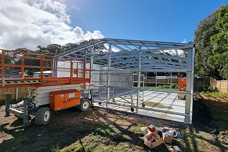 Shed frame getting built with a sissor lift infront.